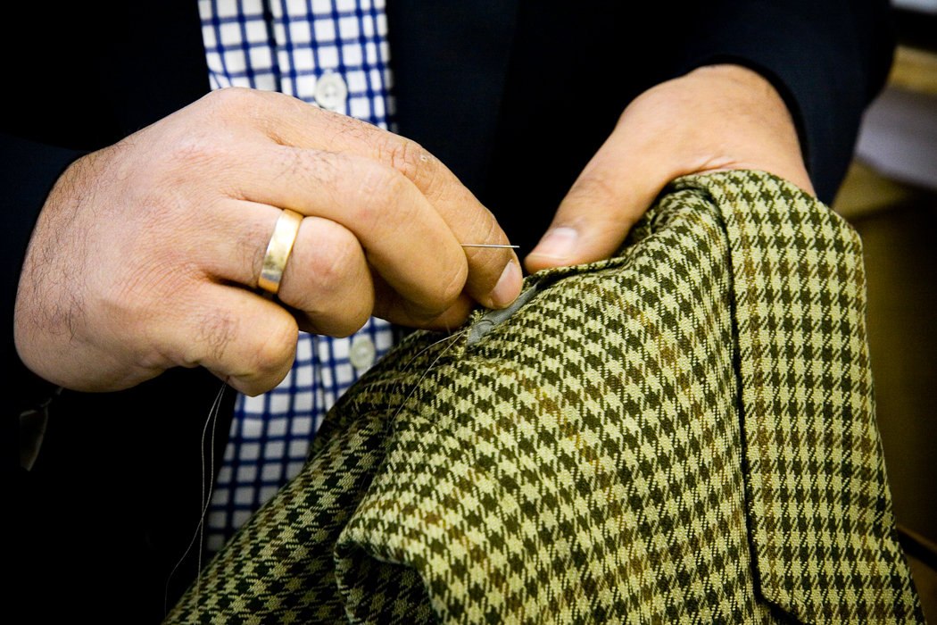 Close-up of hand stitching a checked garment at Harry’s